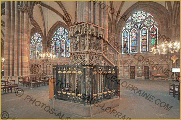 Photo de la chaire de style gothique flamboyant du XVe siècle réalisée par Hans Hammer, avec en fond, les vitraux du bas-côté Nord de la cathédrale Notre-Dame, dans le centre historique de Strasbourg. Histoire et description de l
